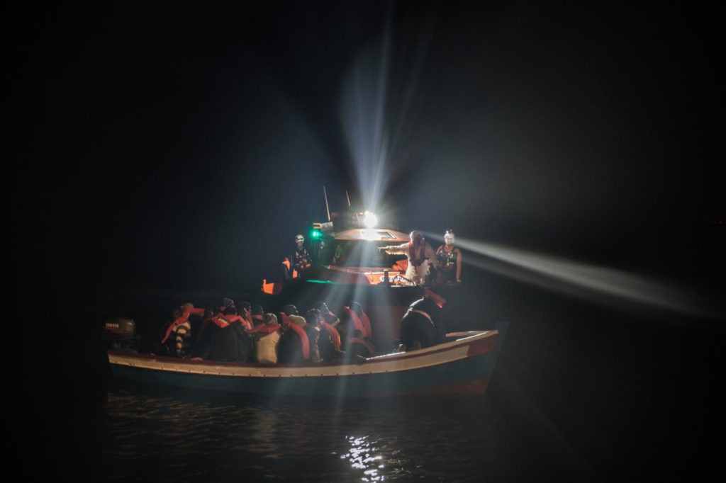 POZZOLLO, ITALY - NOVEMBER 22:  Refugees are escorted to the Topaz Responder in a wooden boat as members of MOAS, Migrant Offshore Aid Station make rescues at sea on November 22, 2016 in Pozzollo Italy. The MOAS team worked through the night and into the next morning rescuing 'approximately' 600 people from vessels. MOAS are currently patrolling international waters off the coast of Libya, and running rescue missions for the many migrants and refugees who continue to attempt to make the dangerous crossing across the Mediterranean Sea to Italy. MOAS are a Malta based registered foundation dedicated to providing professional search-and-rescue assistance to refugees and migrants in distress at sea and work alongside with the Red Cross on board the Topaz Responder. The number of deaths this year of people crossing the Mediterranean has risen to almost 4,300. MOAS alone have rescued around 19,000.  (Photo by Dan Kitwood/Getty Images)