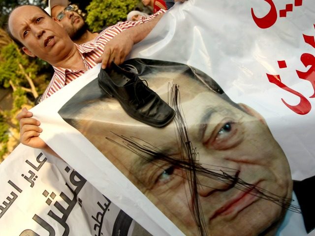 An Egyptian protester puts his shoe on a crossed portrait of Egypt's ousted president