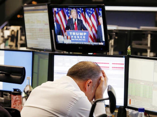 A broker reacts as new elected US President Donald Trump shows up on a television screen a