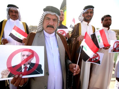 Iraqi tribesmen hold national flags and posters bearing a portrait of Turkish President Recep Tayyip Erdogan crossed out during a protest against the continued presence of Turkish troops in northern Iraq on October 16, 2016 outside the governorate building in the southern city of Basra. Turkish troops are deployed in …