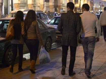 Two young women walk past men who look and talk to them in Rabat on November 24, 2013. A l