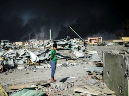 An Iraqi boy looks on as people collect wood and metal at a site which was targeted by an