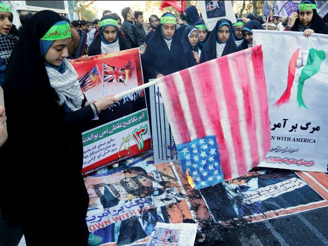An Iranian youth burns home-made American flag outside the former US embassy in the Irania