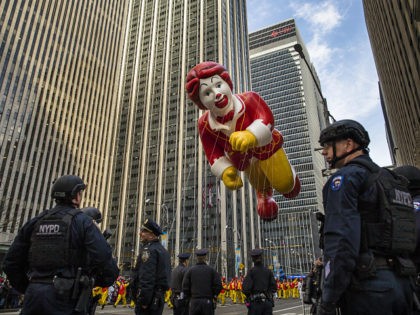 The Ronald McDonald balloon makes its way across Sixth Avenue as heavily armed police stan