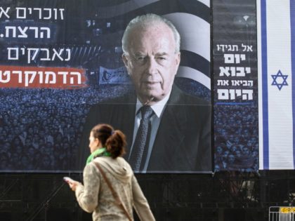An Israeli woman walks past a billboard bearing a portrait of late Israeli prime minister