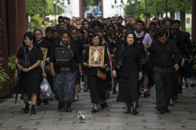 Mourners dressed in black walk through the grounds of the Grand Palace on their way to the