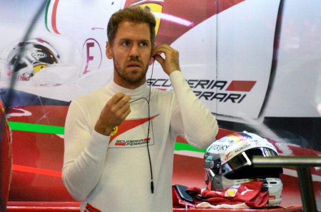 Scuderia Ferrari's German driver Sebastian Vettel, gets prepared at the pits area during t