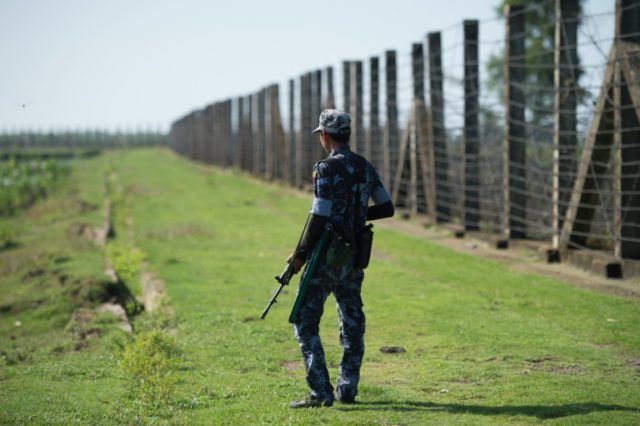A military officer patrols the border fence along the river dividing Myanmar and Banglades