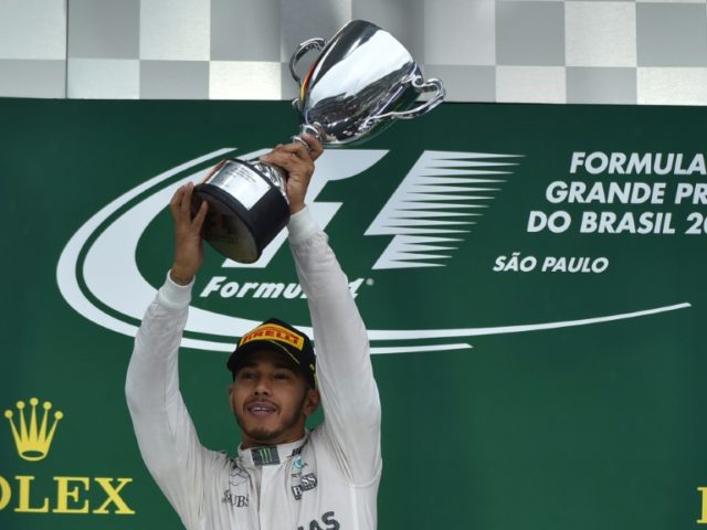 Mercedes driver Lewis Hamilton celebrates with the trophy after winning the Brazilian Gran