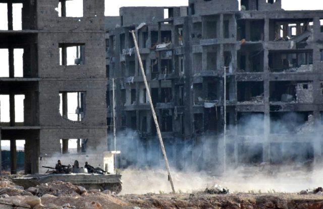 Syrian pro-government forces drive past heavily damaged buildings in Aleppo on November 8,