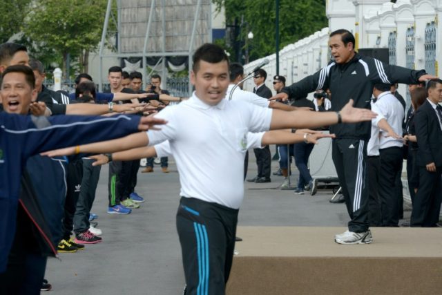 Prayut Chan-O-cha (right) exercises with government officials at the Government House in B