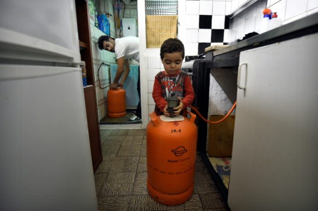 Mohamed Chairi and his two-year-old son Badder change a butane gas bottle in their home in