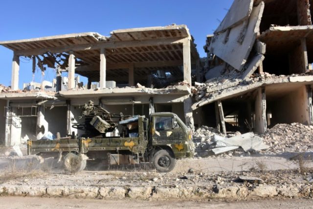 Syrian pro-government forces drive past damaged buildings in the Masaken Hanano district i