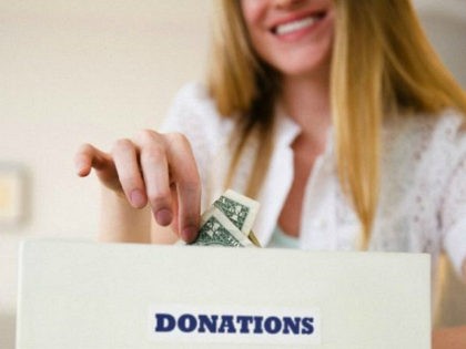 woman-puts-money-in-donation-box-getty