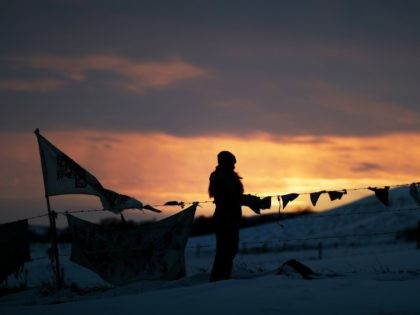 A woman watches the sunset at the Oceti Sakowin camp where people have gathered to protest the Dakota Access oil pipeline in Cannon Ball, N.D., Friday, Dec. 2, 2016. Hundreds of protesters fighting the Dakota Access pipeline have shrugged off the heavy snow, icy winds and frigid temperatures that have …
