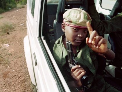 A child with a gun sits in a car on June 09, 1994 with Rwandan Patriotic Front (RPF) partisans patrolling the streets of Kigali, Rwanda. The UN headquarters came under attack as fierce fighting raged in the capital on June 09. (Photo credit should read ABDELHAK SENNA/AFP/Getty Images)