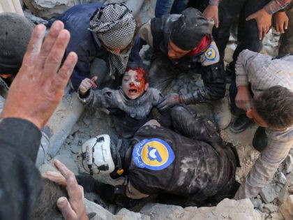 TOPSHOT - Syrian civil defence volunteers, known as the White Helmets, rescue a boy from t
