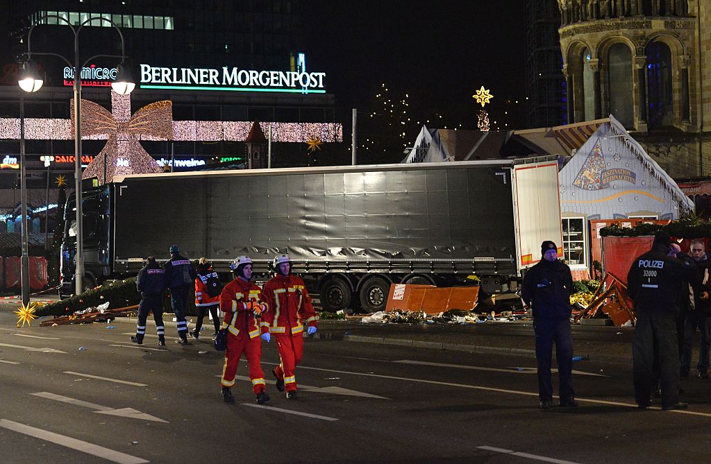 TOPSHOT - Fireworkers pass by the truck that crashed into a christmas market in Berlin, on December 19, 2016 killing at least one person and injuring at least 50 people. Ambulances and police rushed to the scene after the driver drove up the pavement of the market in a central square popular with tourists less than a week before Christmas, in a scene reminiscent of the deadly truck attack in Nice. / AFP / Odd ANDERSEN (Photo credit should read ODD ANDERSEN/AFP/Getty Images)