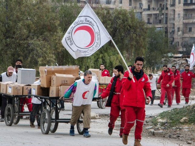 Members of the Syrian Red Crescent escort Syrians and aid supplies from a rebel-controlled