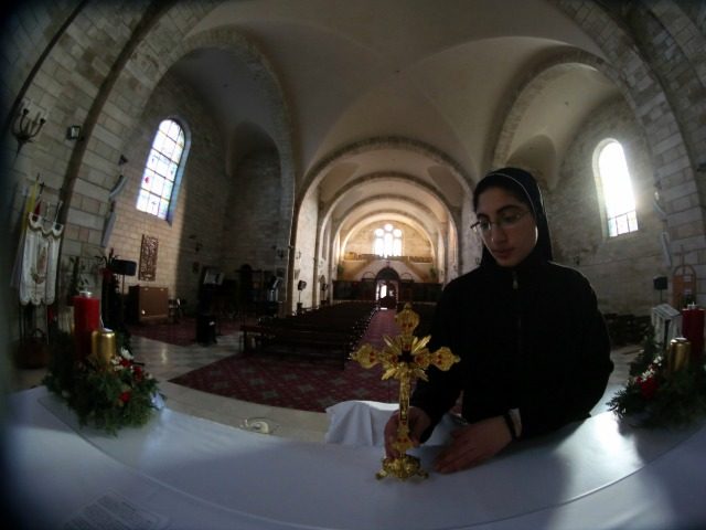A nun places a cross on the alter at a church in the West Bank town of Bir Zeit as she pre