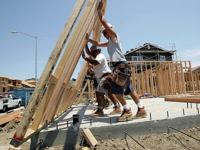 RICHMOND, CA - JUNE 26: Construction workers raise wood framing as they build homes in a new housing development June 26, 2006 in Richmond, California. A report issued by the U.S. Commerce Department stated that sales of new single-family homes were up 4.6 percent in May. The median price of …