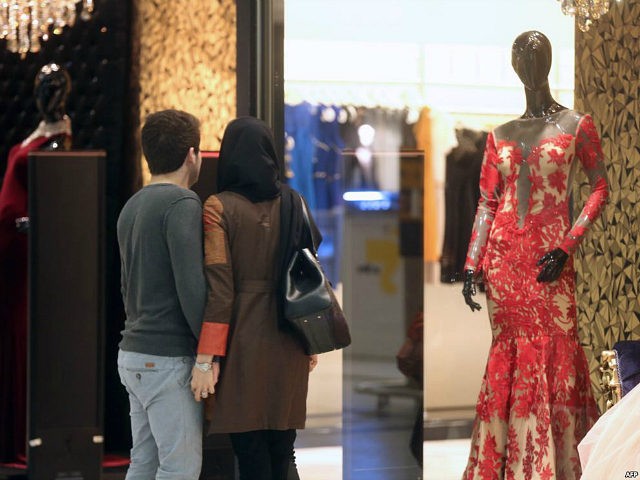 An Iranian couple look at a window display of a shop selling women's clothes at the Laleh