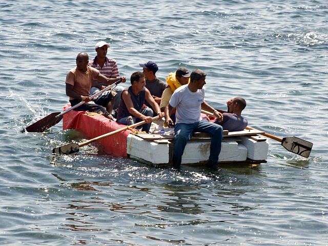 Seven would-be Cuban emigres remain in a homemade boat moments before being arrested by Cuban military agents after their attempt to escape from the island nation was thwarted by the sea currents, on June 4, 2009 in Havana. The boat-people's raft was brought back to the coast just in front of the US Interest Section office in Havana as they tried to cross the shark-infested Florida Straits. The United States, in another move aimed at thawing relations with Cuba, has offered to resume migration talks with the communist-ruled island almost six years after they were suspended. AFP PHOTO/ADALBERTO ROQUE (Photo credit should read ADALBERTO ROQUE/AFP/Getty Images)