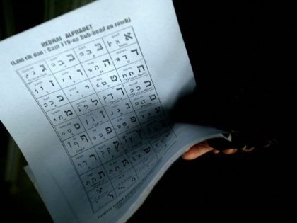 An Indian Jew holds a sheet with letters of the Hebrew alphabet while taking part in a cla