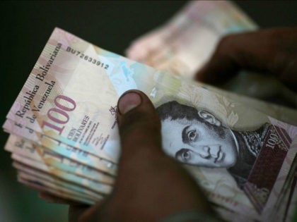 A cashier counts Venezuelan bolivar notes at a street market in downtown Caracas, Venezuel