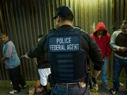 A U.S. Immigration and Customs Enforcement (ICE) agent directs a group of undocumented men
