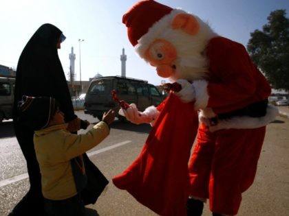 A man dressed in a Santa Claus outfit hands a souvenir to an Iraqi Muslim boy in the Shiite holy city of Najaf on December 17, 2015. AFP PHOTO / HAIDAR HAMDANI / AFP / HAIDAR HAMDANI (Photo credit should read HAIDAR HAMDANI/AFP/Getty Images)