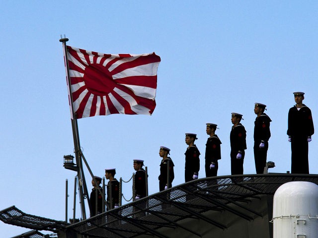 Sailors stand on the deck of the Izumo warship as it departs from the harbor of the Japan