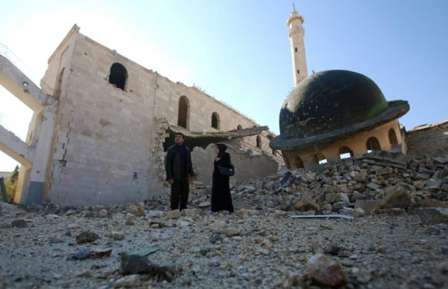 Kefa Jawish (right) and husband Tajeddin Ahmed walk near a destroyed mosque in Aleppo's Ha