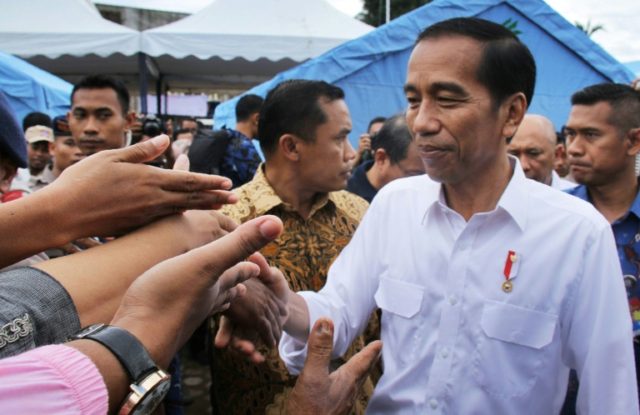 Indonesian President Joko Widodo shakes hands with quake survivors at a temporary shelter