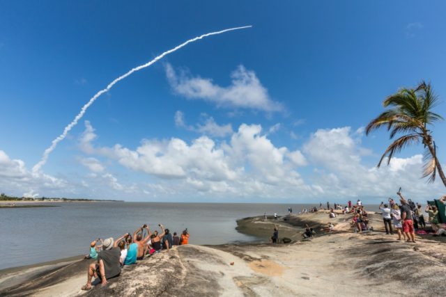 People take photos as an Ariane 5 space rocket with a payload of four Galileo satellites l