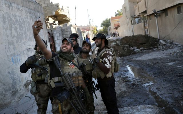 Iraqi soldiers take a selfie on November 22, 2016 on a street in the Aden district of Mosu