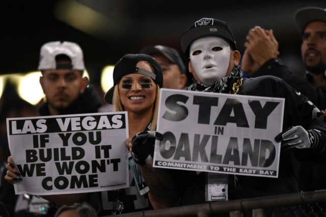 Oakland Raiders fans display signs in support of the team staying in Oakland during their