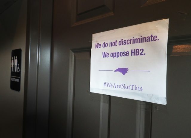 A unisex sign and the "We Are Not This" slogan seen outside a bathroom on May 10, 2016 in