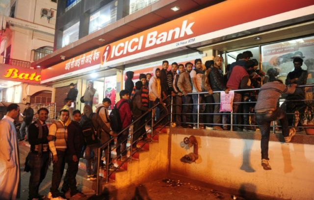 People queue to withdraw money from an ATM in Allahabad