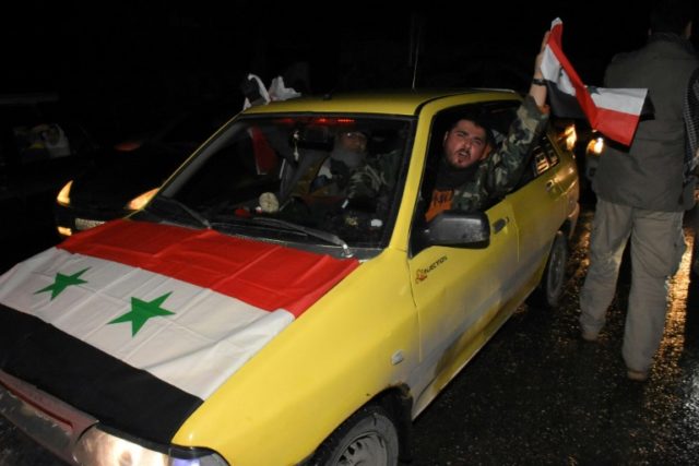 A Syrian driver flies a national flag as people celebrate in the streets on December 22, 2