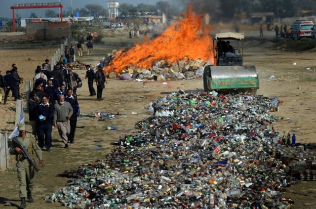 Pakistani customs officials crushing bottles of liquor: sales are banned to Muslims and st