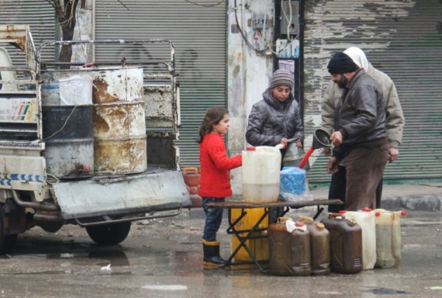 Residents buy petrol on a street in the northwestern Syrian city of Idlib on December 30,