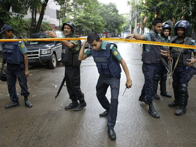 Bangladeshi policemen stand guard in an area cordoned off after heavily armed militants st