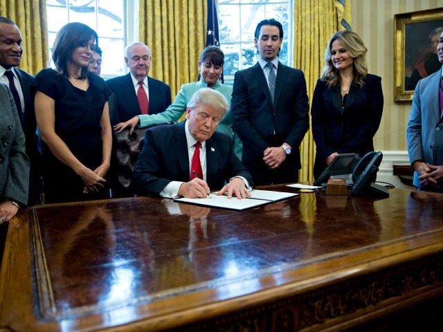 WASHINGTON, DC - JANUARY 30: (AFP OUT) U.S. President Donald Trump signs an executive order in the Oval Office of the White House surrounded by small business leaders January 30, 2017 in Washington, DC. Trump said he will dramatically reduce regulations overall with this executive action as it requires that …