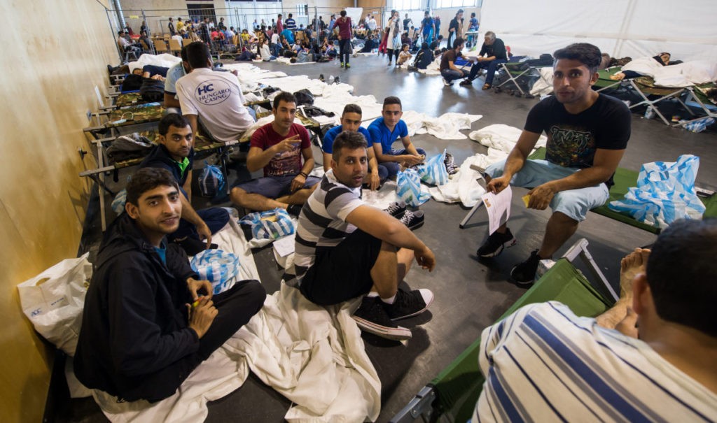 PASSAU, GERMANY - JULY 15: Refugees from Afghanistan who arrived in Germany by crossing the nearby Austrian border wait in the relaxation zone after being registered at the X-Point Halle initial registration center of the German federal police (Bundespolizei) on July 15, 2015 near Passau, Germany. Refugees, mostly from Syria, Iraq, Afghanistan and the Balkans, are currently arriving at a rate of up to one thousand per day in Bavaria. German police opened the X-Point Halle center, where refugees are identified, registered and undergo a security check, in an effort to cope with the record influx. After six to ten hours of waiting the refugees are brought to a preliminary refugee registration camp (Erstaufnahmelager), from which they are later transferred to other refugee facilities across the country. Germany has become one of the main destination countries for refugees seeking asylum in Europe and this year Germany expects over 400,000 refugees to arrive. (Photo by Joerg Koch/Getty Images)