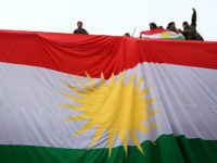 TOPSHOT - Iraqi Kurdish youths wave a national flag as they stand above a giant flag of Kurdistan during celebrations of Flag Day on December 17, 2015 in Arbil, the capital of the autonomous Kurdish region in northern Iraq. / AFP / SAFIN HAMED (Photo credit should read SAFIN HAMED/AFP/Getty …