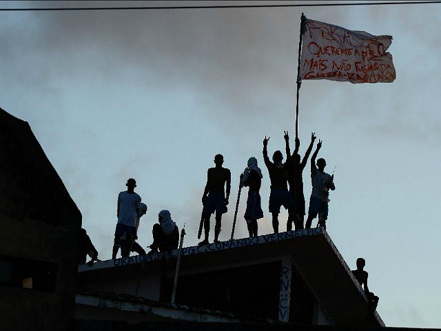Prisioners atop the roof of the compound celebrate the transfer of their leaders after a n