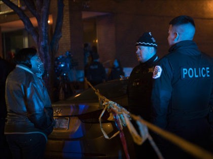 A woman talks with members of the Chicago Police Department at the scene where at least si