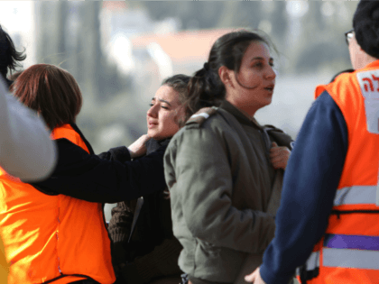 Israeli medical personnel assist an Israeli female soldier who was an eye witness to the a
