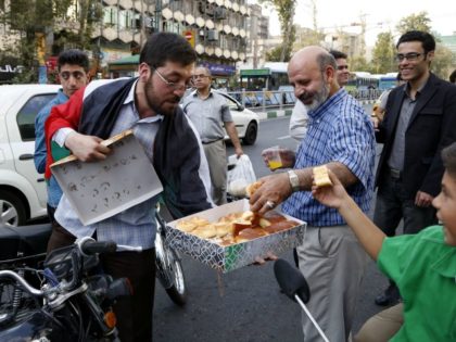 n Iranian man hands out sweets in a street in Tehran on August 27, 2014 to celebrate the e